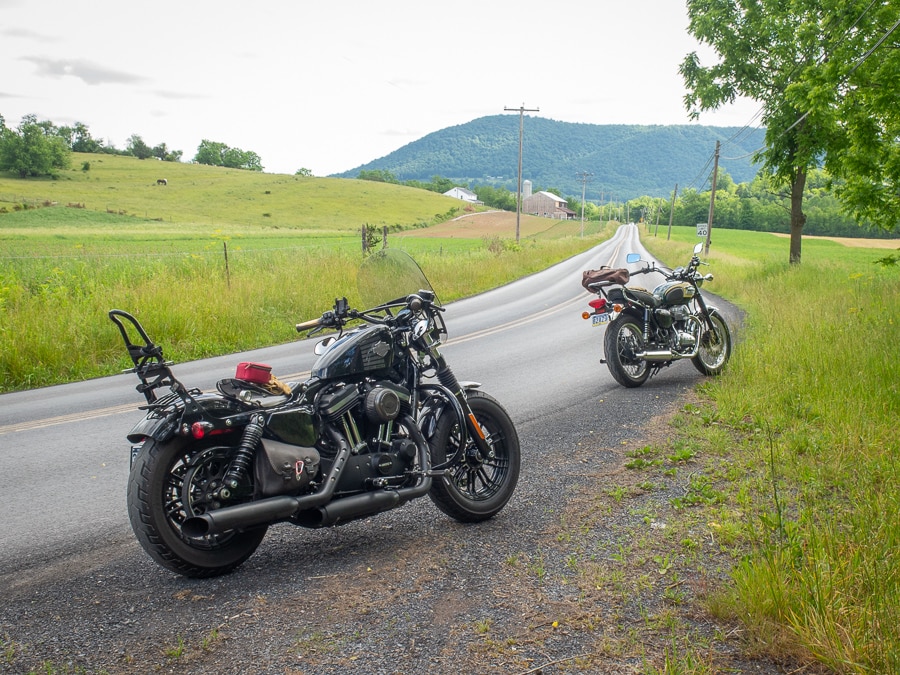 Two motorcycles parked along a rural road.