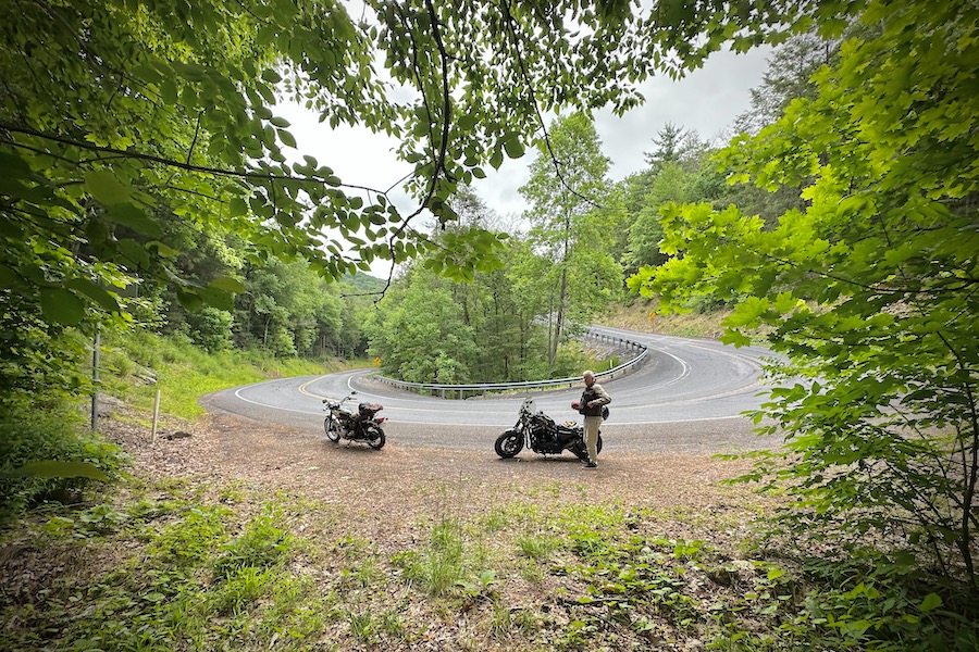 Two motorcycles parked along a hairpin turn.