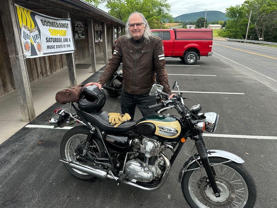 Steve Williams standing with his 2001 Kawasaki W650 motorcycle outside a tavern.