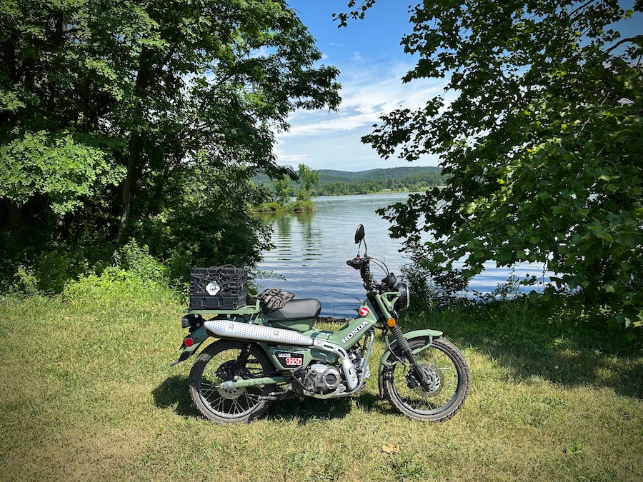 Honda CT125 parked next to a lake.