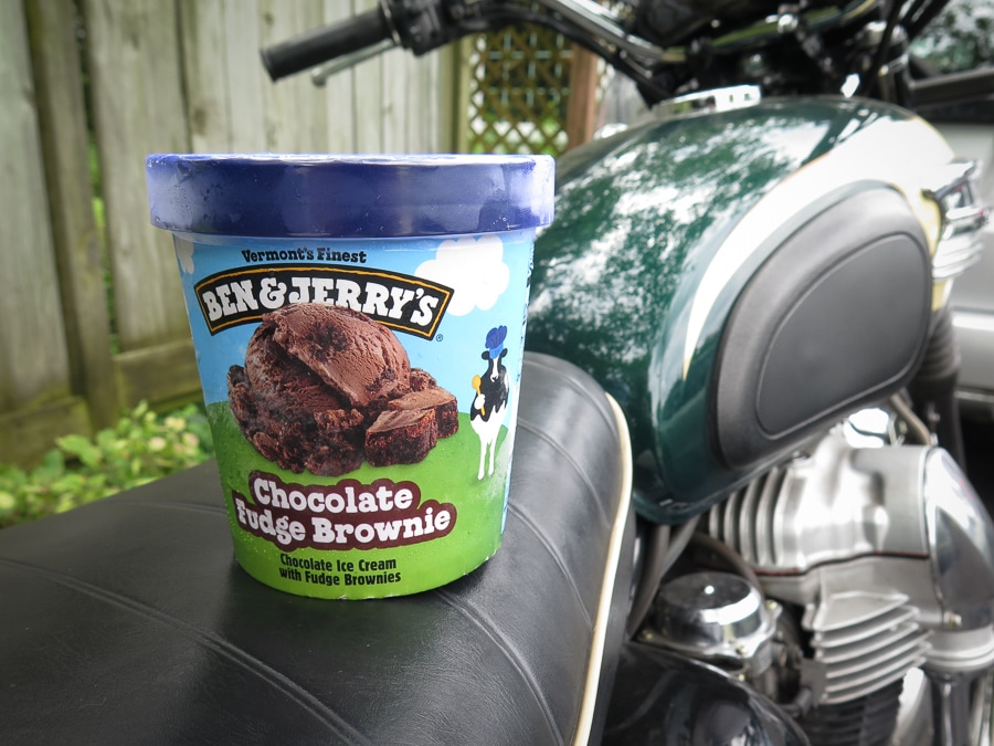 A pint of Ben & Jerry's ice cream sitting on the seat of a motorcycle.
