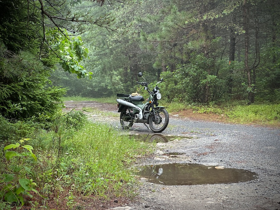 Honda Trail 125 motorcycle on a wet gravel road.