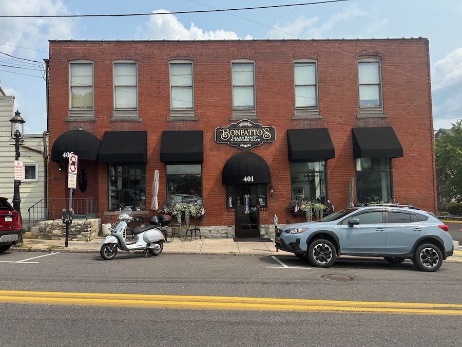 A Vespa GTS scooter parked outside of Bonfatto's Italian Market & Cafe.