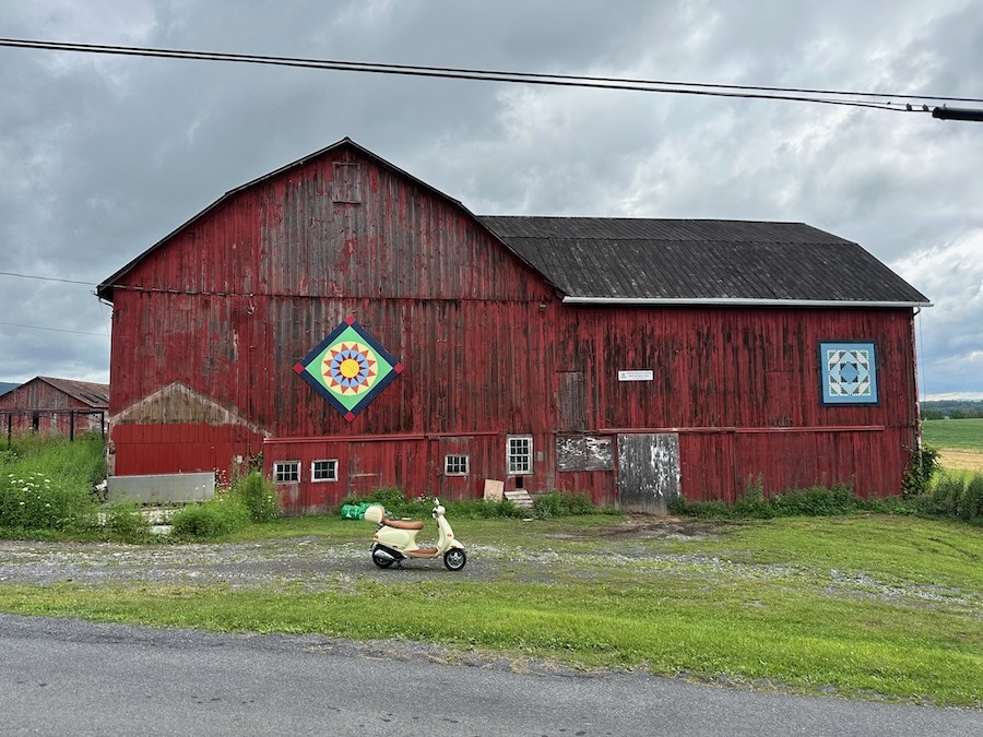 A 2005 Vespa ET4 scooter parked in front of a red barn.