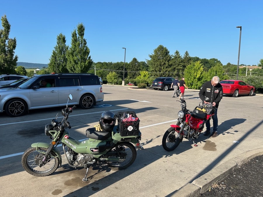 Two Honda Trail 125 motorcycles at a convenience store.