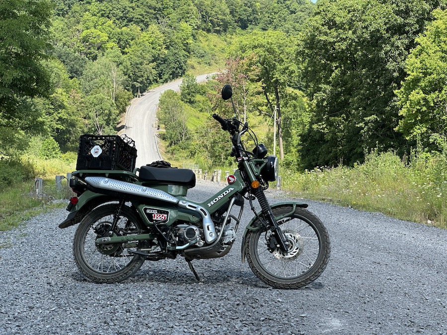 A Honda Trail 125 motorcycle parked in the middle of a gravel road.
