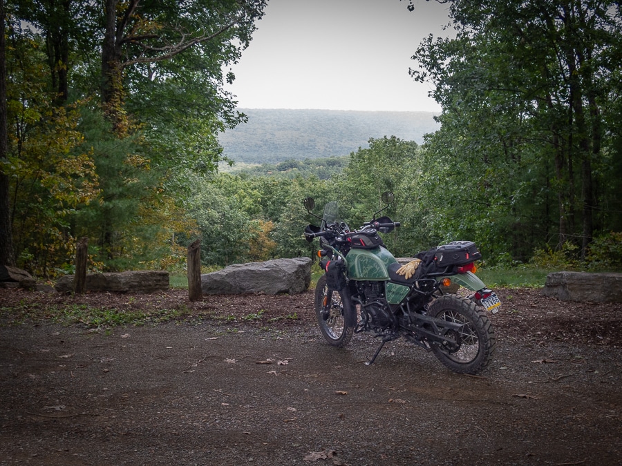 A Royal Enfield Himalayan parked at a forest overlook.