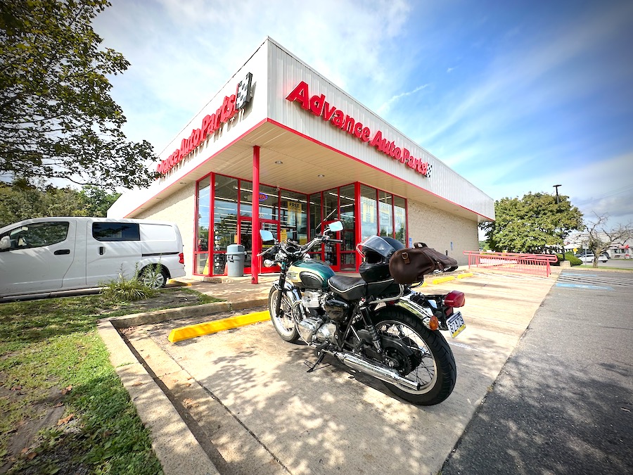 A motorcycle parked at an auto parts store.