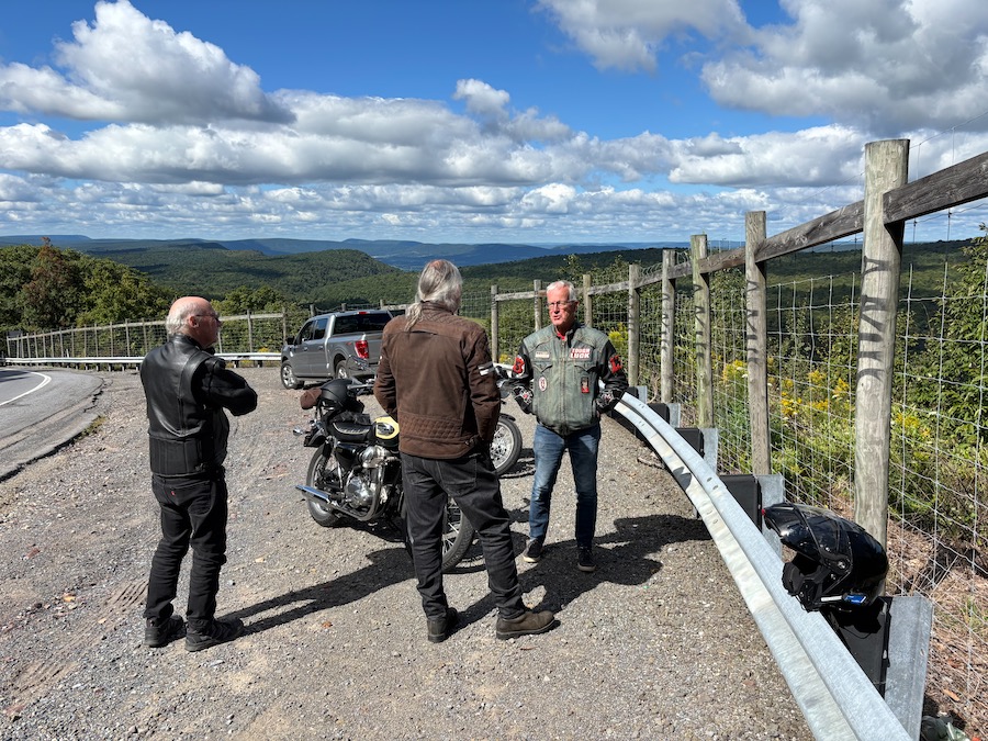 Men and motorcycles at a scenic vista.