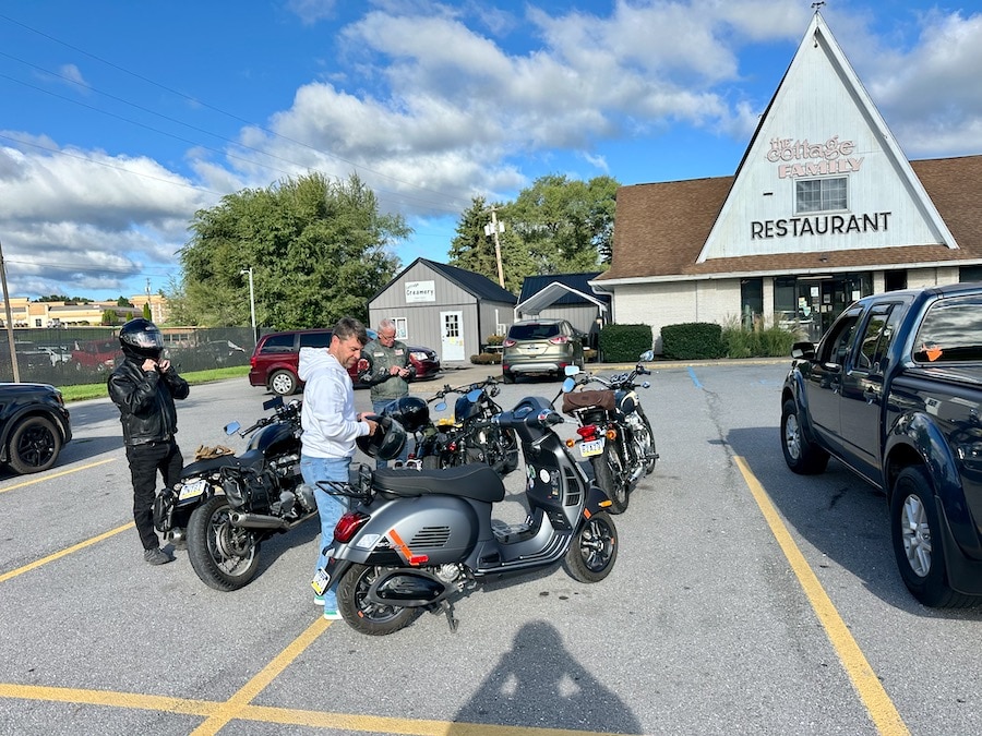 A scooter and motorcycles parked outside The Cottage Restaurant.