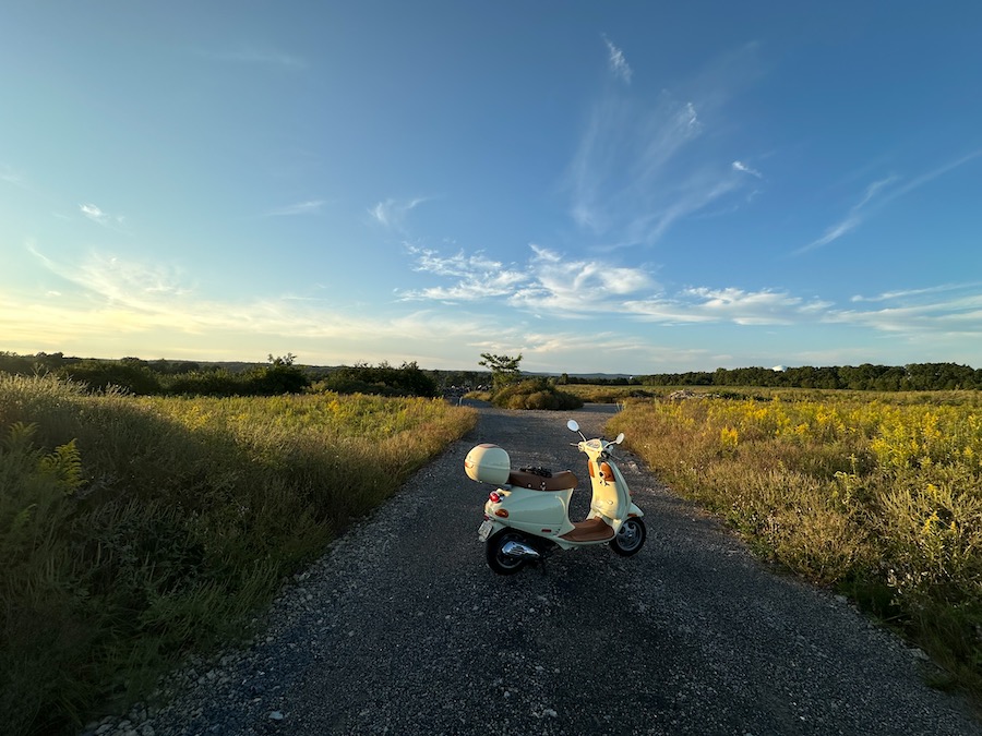 The Vespa ET4 scooter parked on a gravel road as the sun goes down.