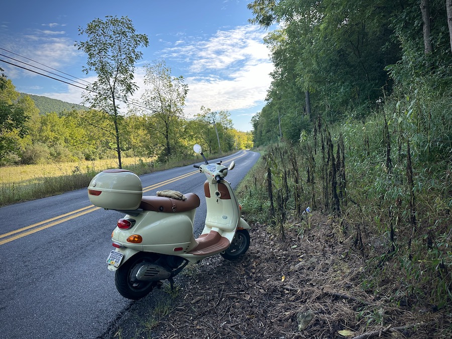 A Vespa ET4 along a rural road early in the morning.