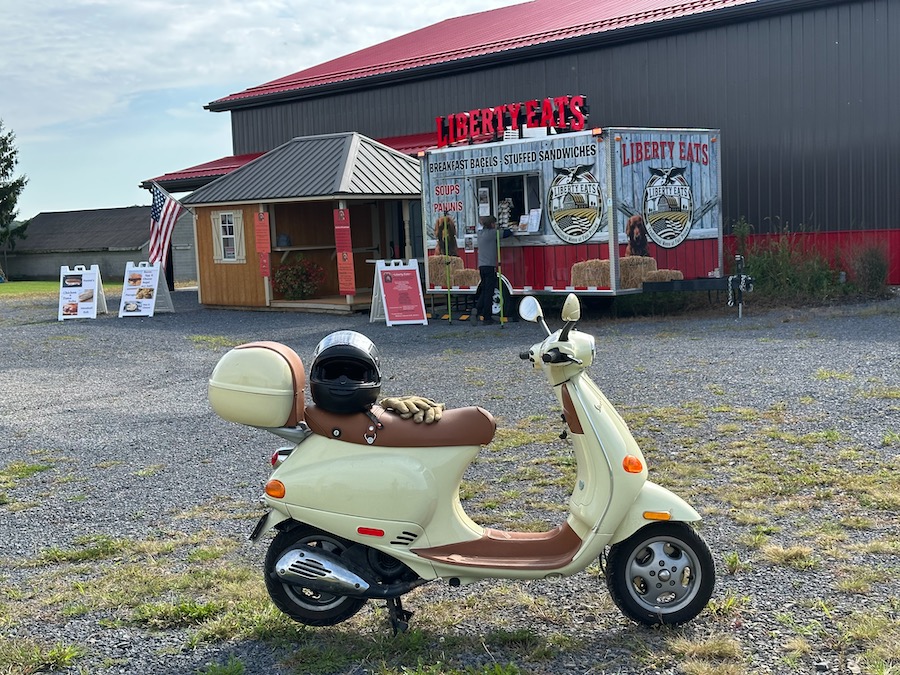 A Vespa ET4 scooter parked at a food trailer.