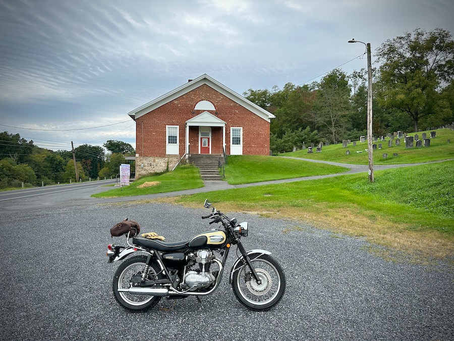A 2001 Kawasaki W650 motorcycle parked in front of a small rural church.