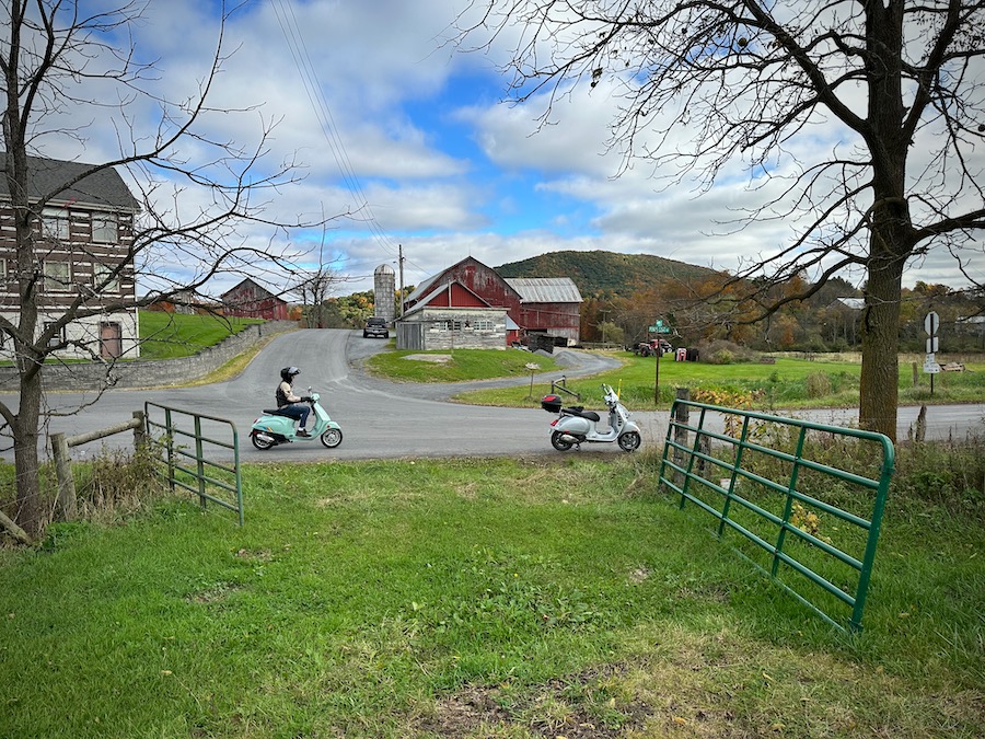 Two scooters at a rural intersection.